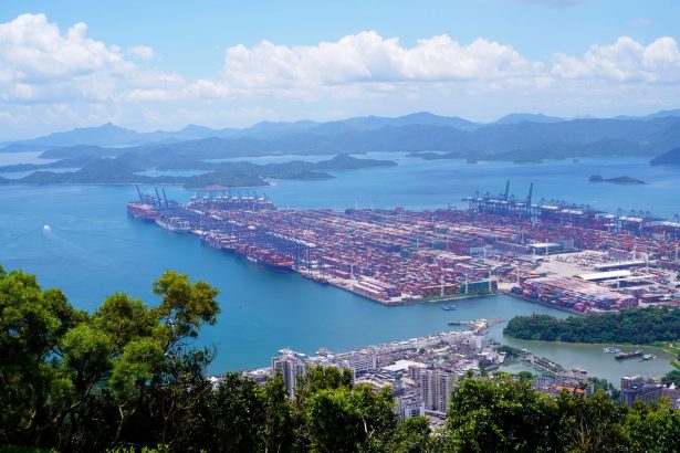 Vista aérea de um porto industrial com navios e contêineres em uma área costeira.