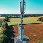 Torre de telefonia celular em meio a uma extensa área de cultivo.